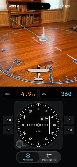 A virtual VOR station on a wooden floor with a compass rose, a small aircraft marker, and the VOR receiver below reading course 360, TO, DME 4.9 feet